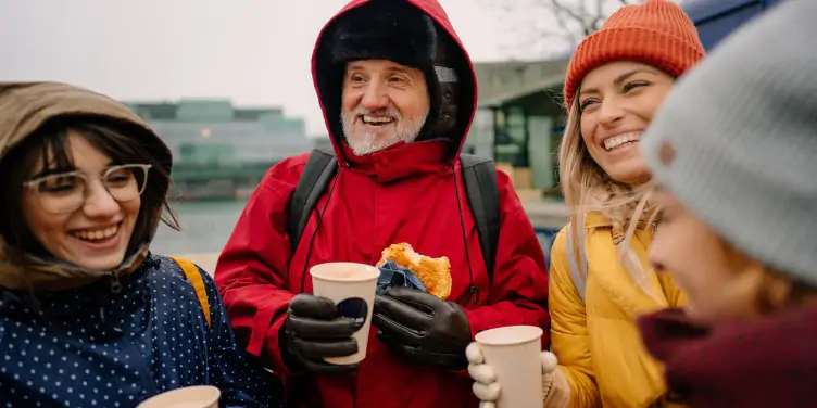 Huddled group of adults happily enjoying a snack and hot drinks while on holiday