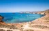 Beautiful sunny beach in Murcia, with the boats moored up in the sea and tourists on the beach.