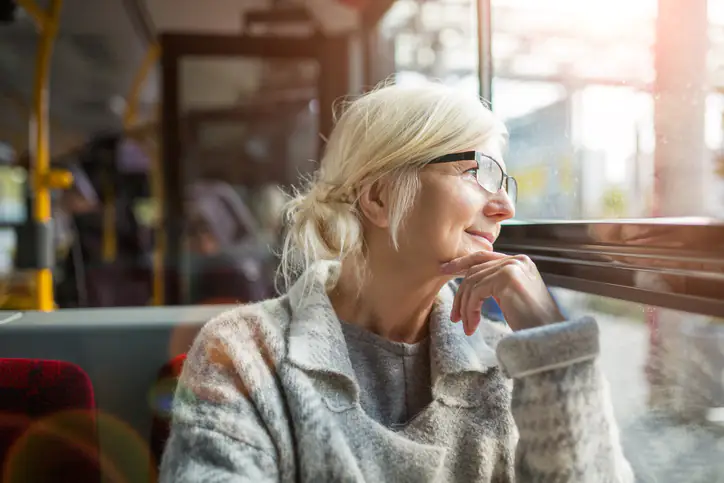an image of Senior Woman Looking Through Window While Traveling In Bus
